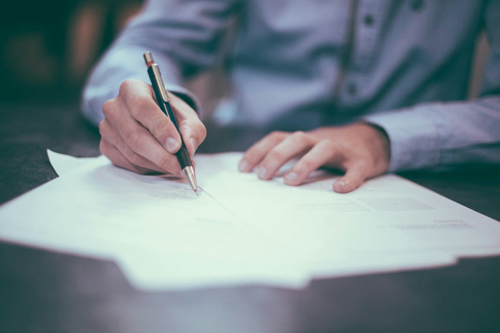Business owner signing government-backed loan documents at a desk